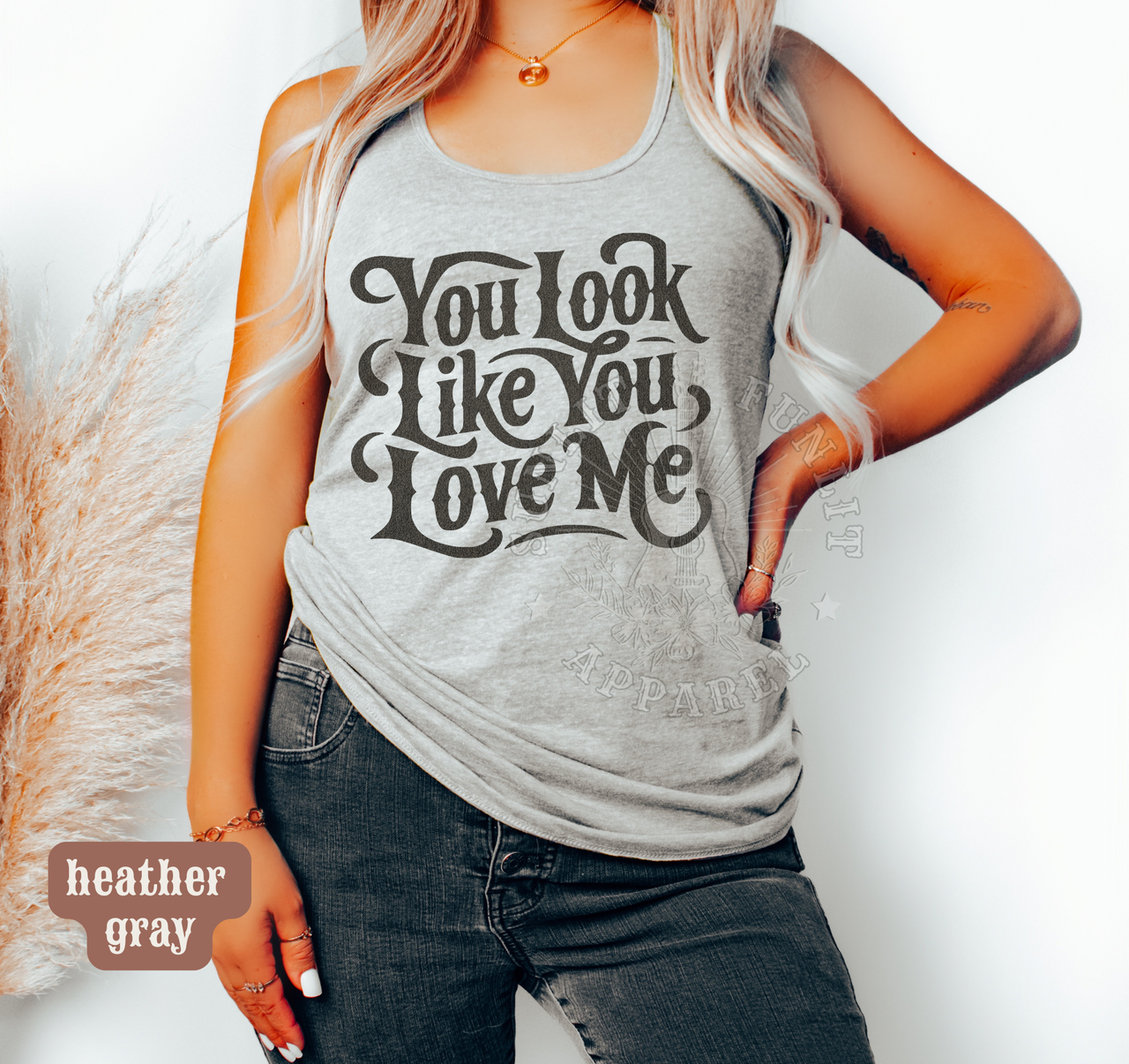 A woman wearing a gray tank top with the text "You look like you love me" printed on it.