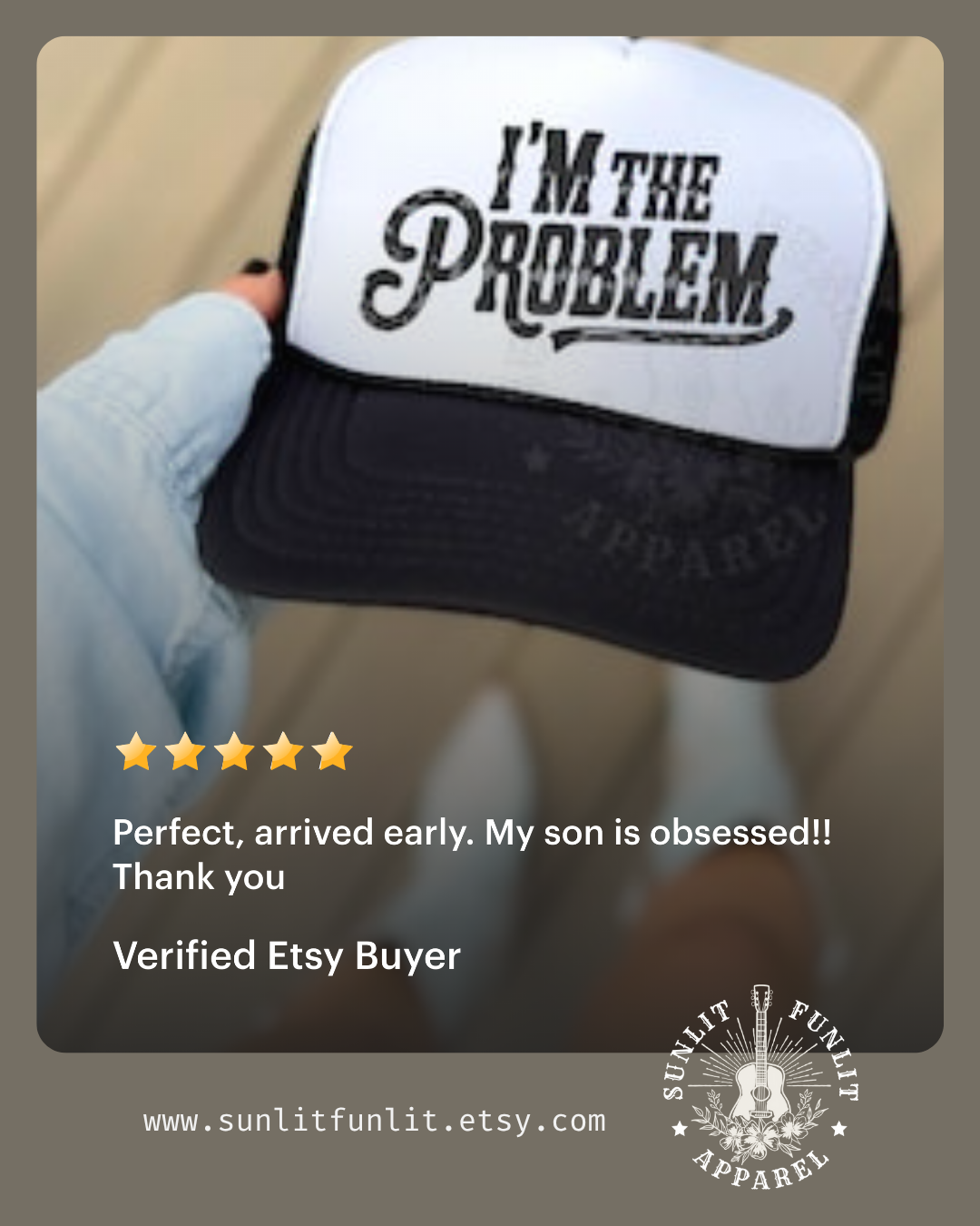 A person is holding a black and white baseball cap with the text "I'm the problem" printed on it.