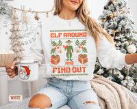 Thumbnail for A woman wearing a white sweater with a Christmas-themed design and text, holding a mug with a Santa Claus image, and sitting in front of a Christmas tree.