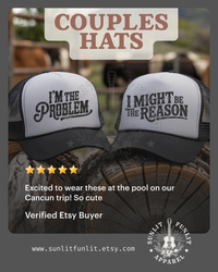 Thumbnail for two black and white baseball caps with humorous text printed on them, placed on a wooden surface.