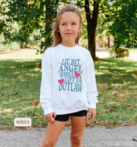 Thumbnail for A young girl wearing a white sweatshirt with text printed on it, standing in a park surrounded by trees.