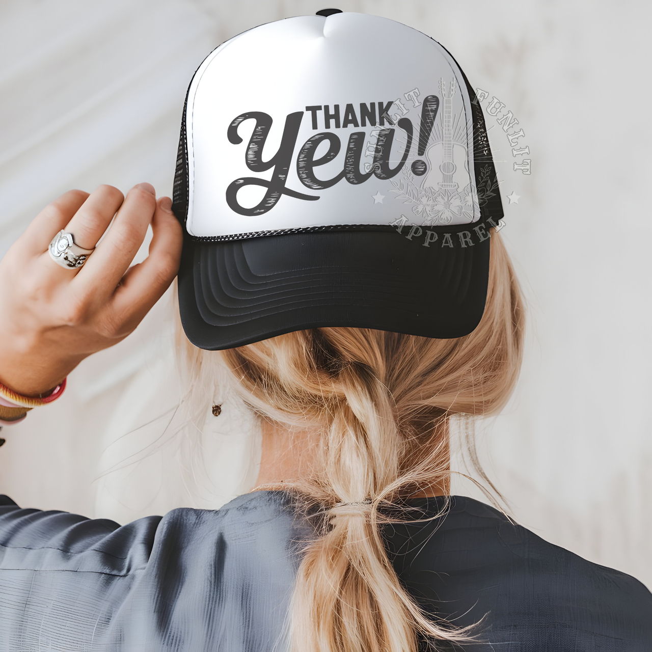 A person wearing a black and white baseball cap with the text "THANK YEE!" printed on it.
