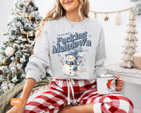 Thumbnail for A woman wearing a gray sweatshirt with a snowman graphic and the text 