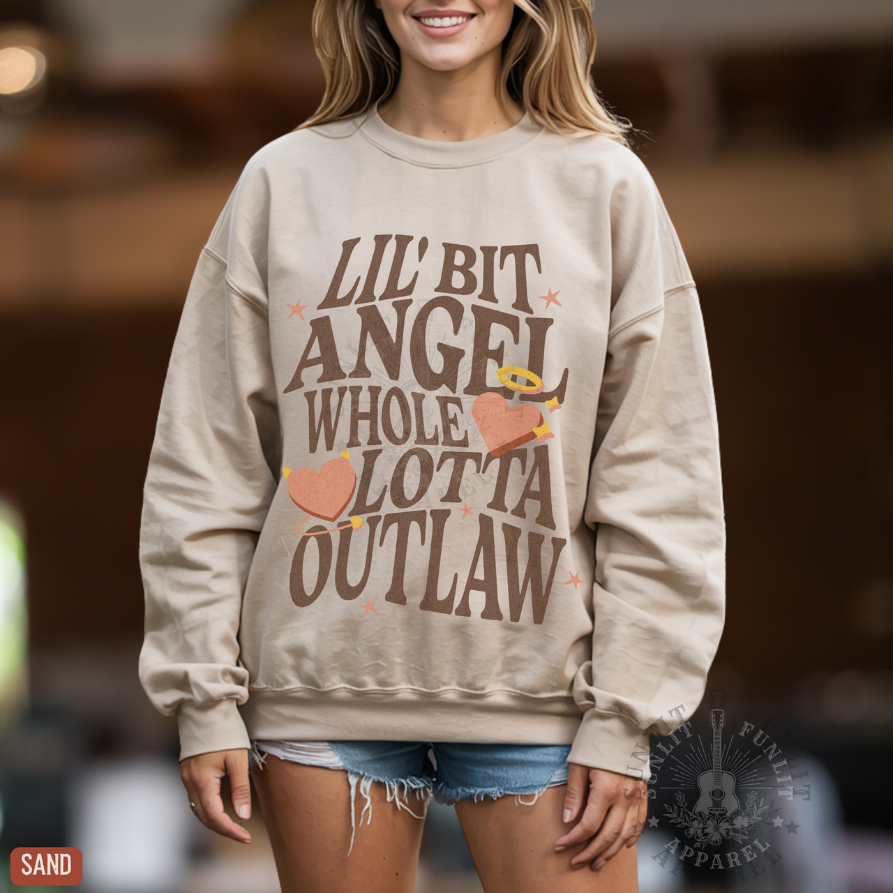A woman wearing a beige sweatshirt with a graphic design printed on it.