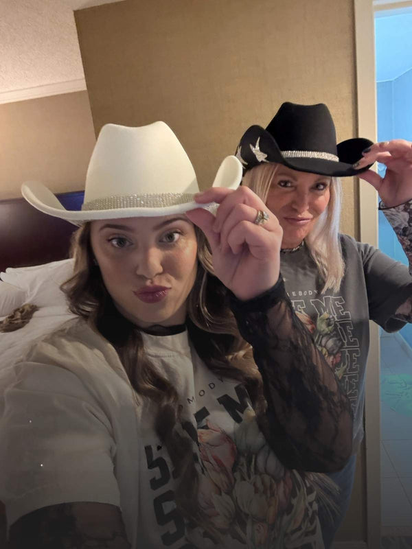 Two people wearing cowboy hats in a room with a bed and window.