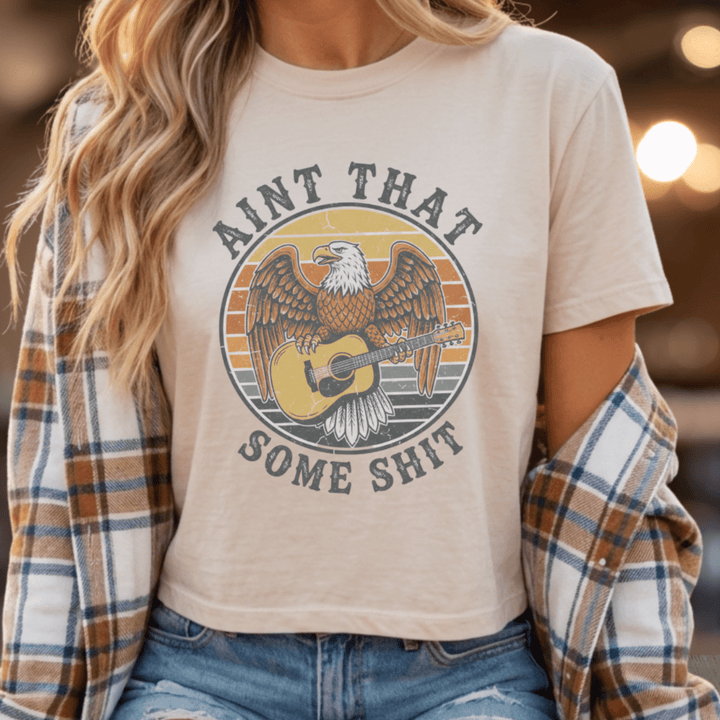 Person wearing a t-shirt with an eagle and guitar graphic and text.