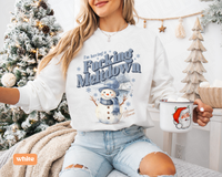 Thumbnail for A woman wearing a white sweatshirt with a snowman graphic and the text 