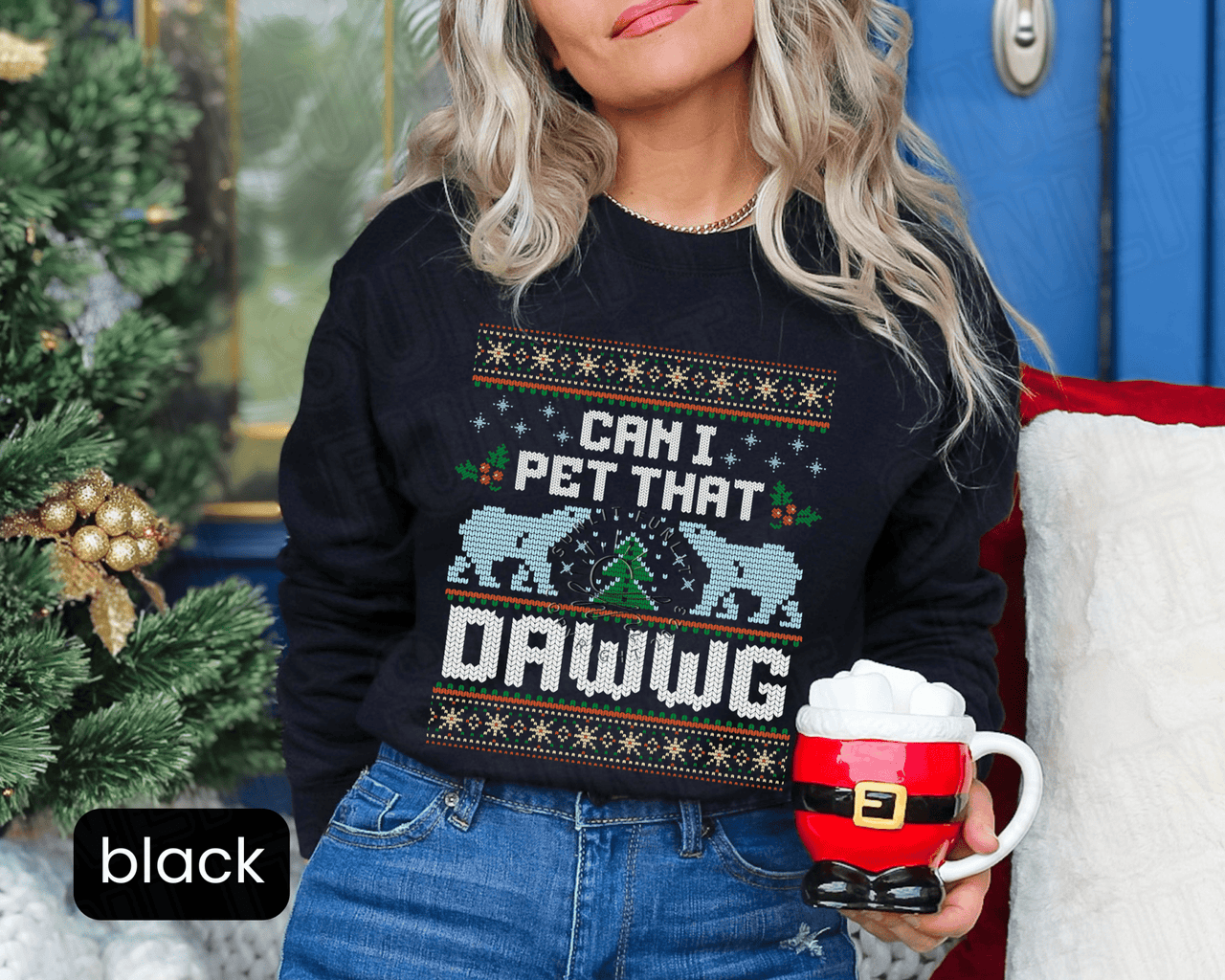 A woman wearing a black sweater with a Christmas-themed design and holding a mug with a Santa Claus figure.