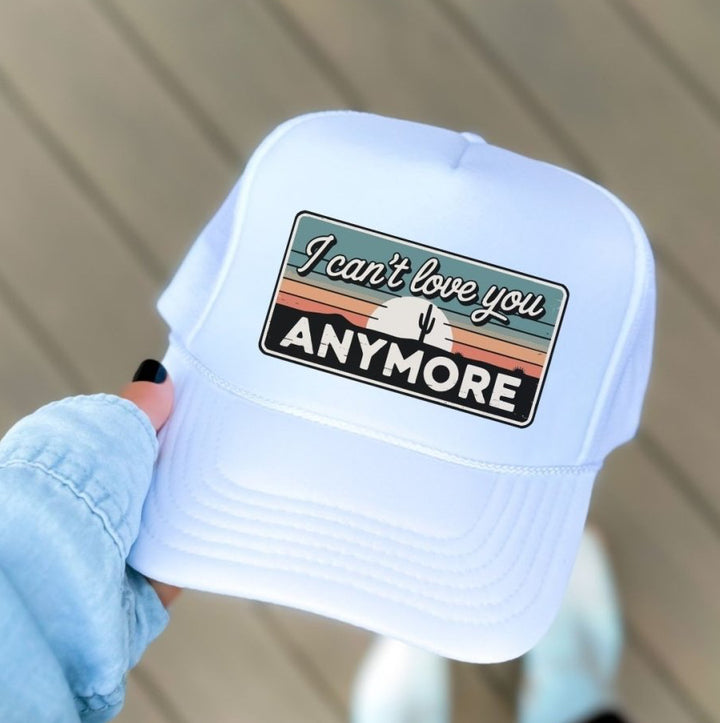 White cap with a colorful graphic and text held by a person.