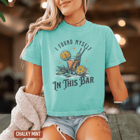 Thumbnail for A woman wearing a teal t-shirt with a graphic design of a cocktail and the text 