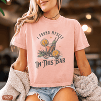 Thumbnail for A woman wearing a pink t-shirt with a graphic design of a cocktail and the text 