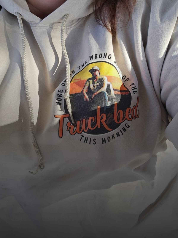 White hoodie with graphic design of a person in a truck bed and text.
