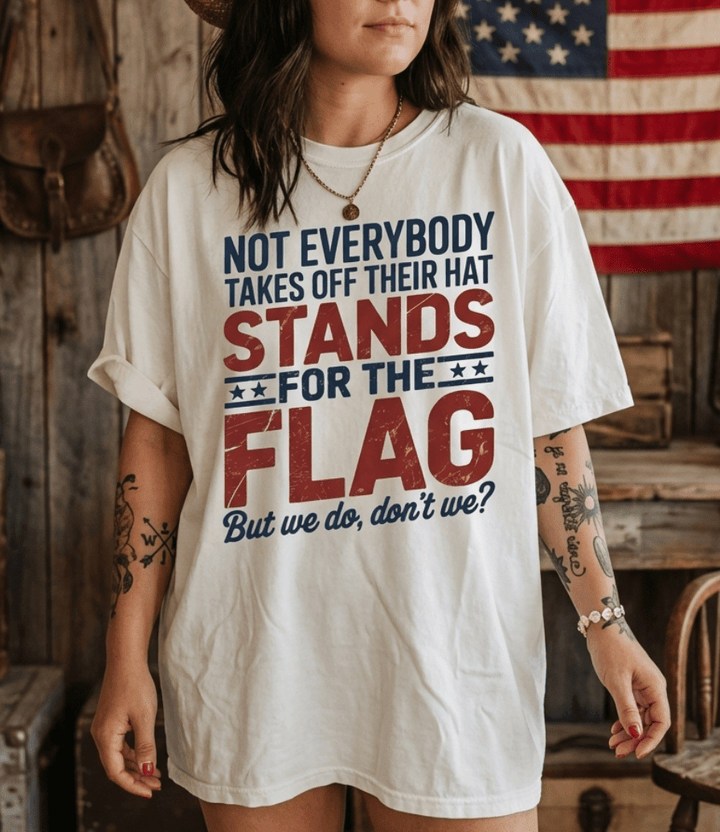 Woman wearing a white t-shirt with a patriotic message in a rustic setting with an American flag.