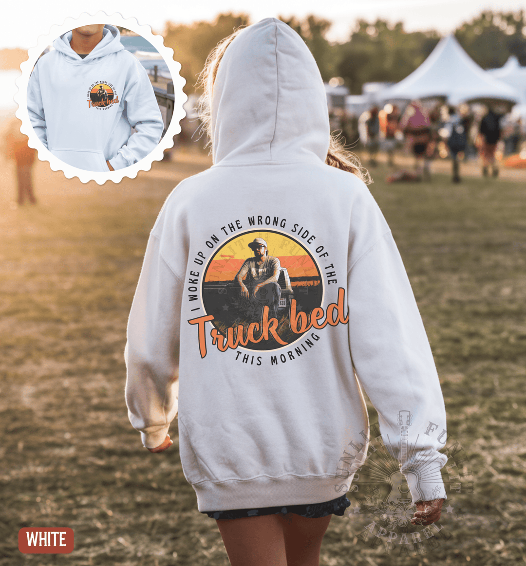 A person wearing a white hoodie with a graphic design on the back is walking in a field.