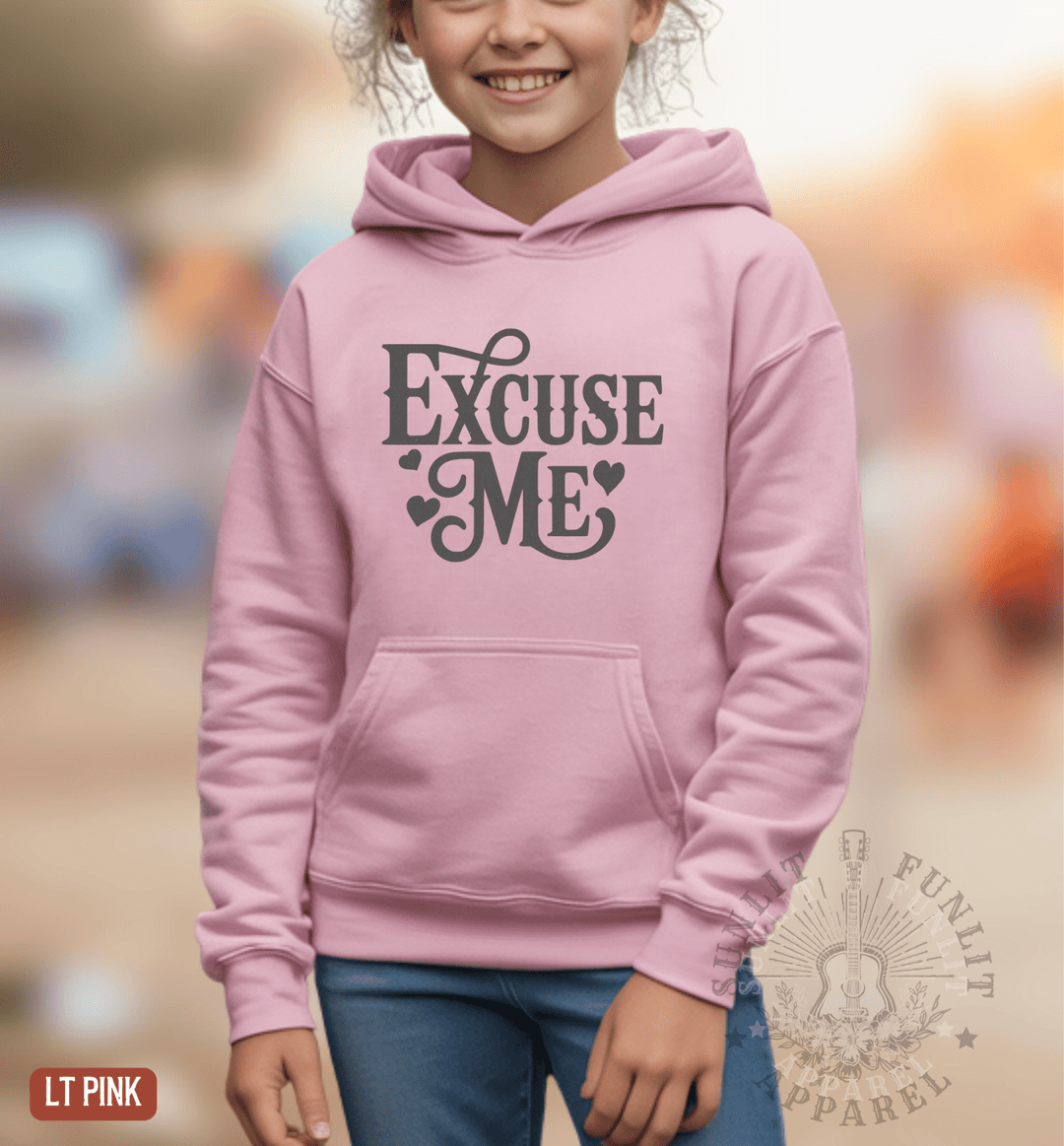 A young girl wearing a pink hoodie with the text "Excise Me" printed on it.